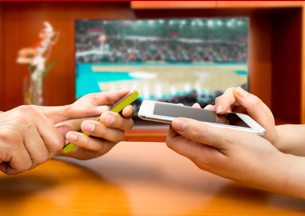 Friends using mobile phone and betting during a basketball match - HQZ Friends using mobile phone and betting during a basketball match