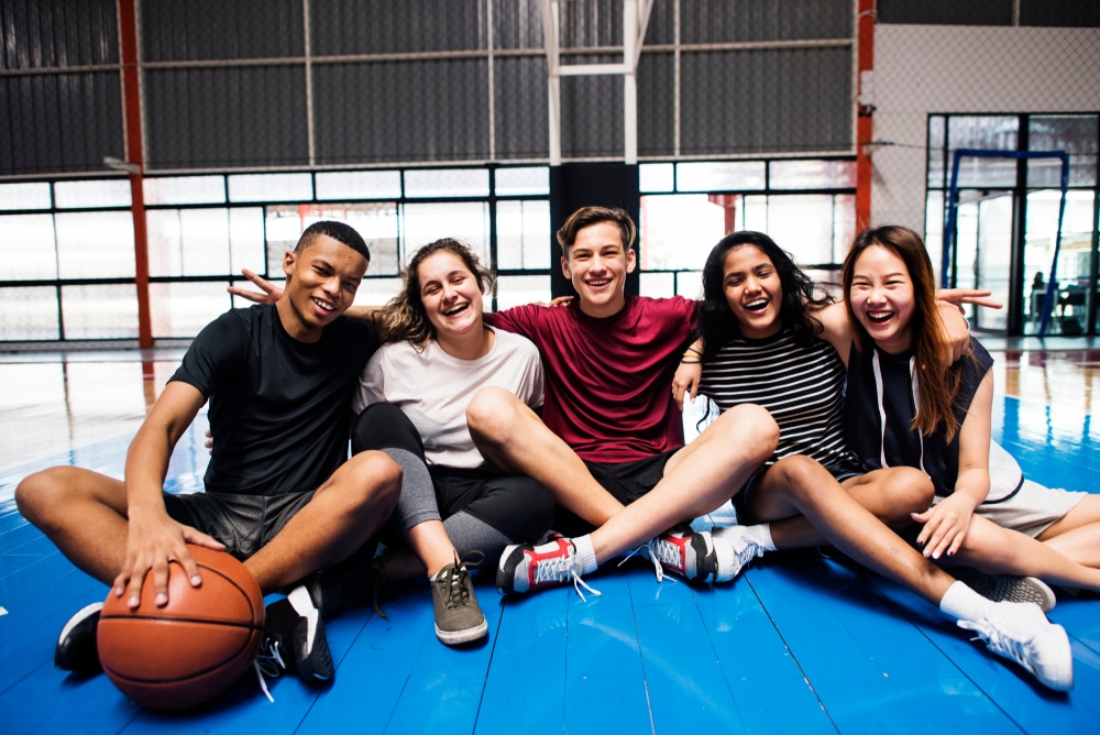 GroupOfYoungTeenagerFriendsOnABasketballCourtRelaxing - HQZ