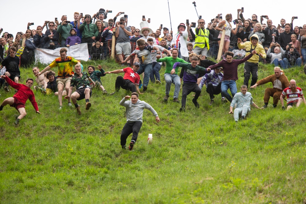 Brockworth, England, UK, May 27th 2019. Eventual winner (front left) Max McDougall chases the cheese during the annual Spring bank holiday cheese-rolling event at Cooper's Hill near Gloucester.