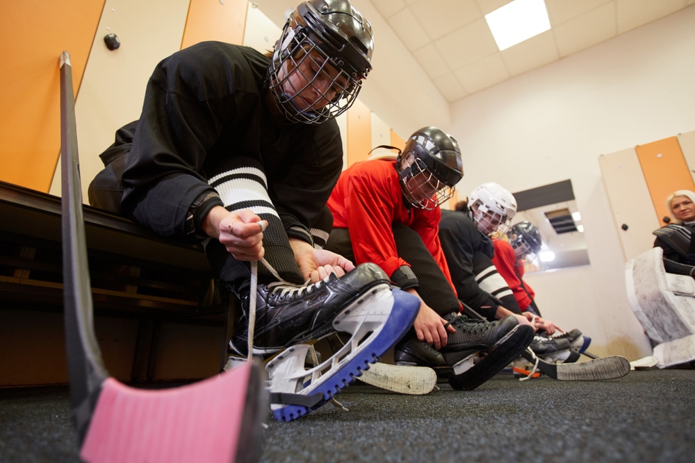 Low angle view at female hockey team putting on gear in locker room while preparing for match or practice, copy space